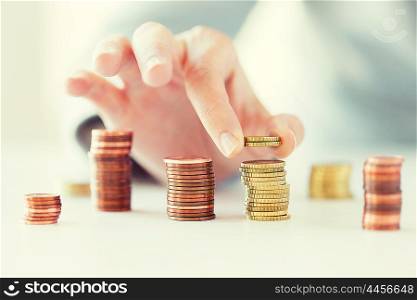 business and money saving concept - close up of female hand putting euro coins into columns in office. close up of female hand putting coins into columns