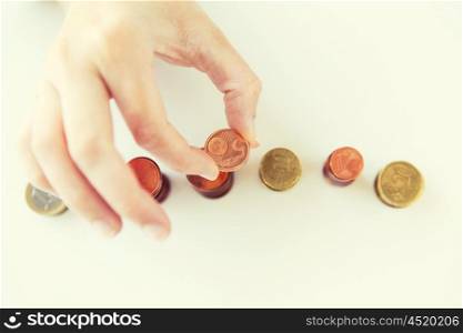 business and money saving concept - close up of female hand putting euro coins into columns in office. close up of female hand putting coins into columns
