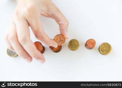 business and money saving concept - close up of female hand putting euro coins into columns in office. close up of female hand putting coins into columns