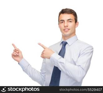business and office, advertising, people concept - friendly young buisnessman pointing finger to something on virtual screen