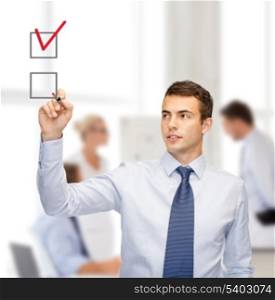 business and office concept - attractive buisnessman or teacher with marker drawning red checkmark into checkbox