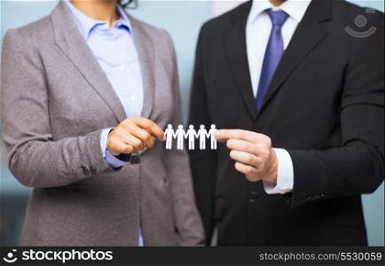 business and office concept - businessman and businesswoman holding paper team in office