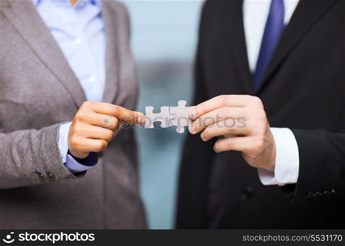 business and office concept - businessman and businesswoman holding puzzle pieces in office