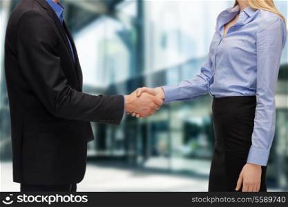business and office concept - businessman and businesswoman shaking hands outdoors