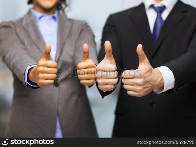 business and office concept - businessman and businesswoman showing thumbs up in office