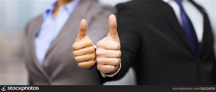 business and office concept - businessman and businesswoman showing thumbs up in office. businessman and businesswoman showing thumbs up