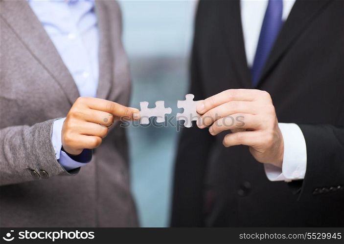 business and office concept - businessman and businesswoman trying to connect puzzle pieces in office