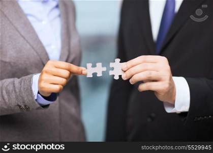 business and office concept - businessman and businesswoman trying to connect puzzle pieces in office