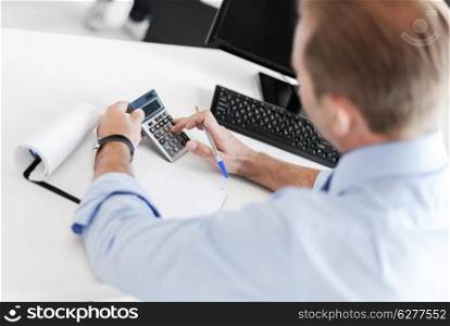 business and office concept - businessman with notebook and calculator