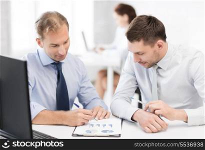 business and office concept - businessmen with notebook discussing graphs on meeting