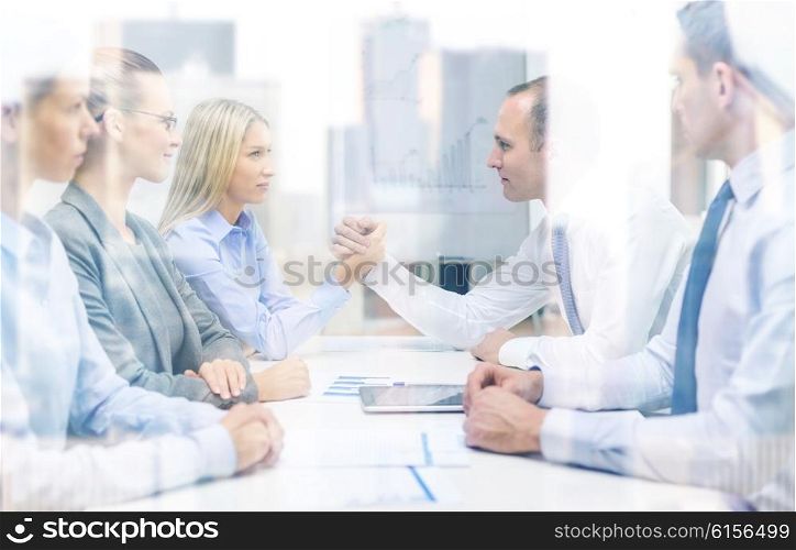 business and office concept - businesswoman and businessman arm wrestling during meeting in office. businesswoman and businessman arm wrestling