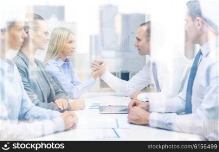 business and office concept - businesswoman and businessman arm wrestling during meeting in office. businesswoman and businessman arm wrestling