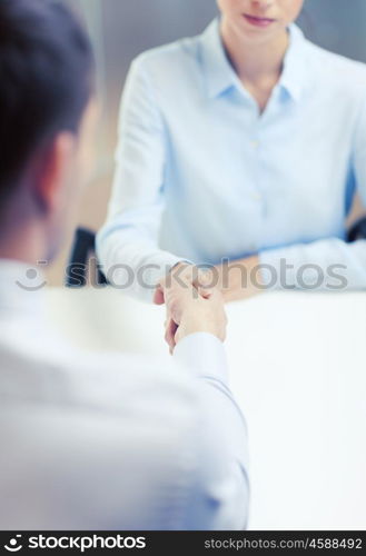 business and office concept - businesswoman and businessman shaking hands in office. businesswoman and businessman shaking hands