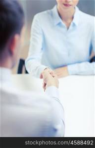 business and office concept - businesswoman and businessman shaking hands in office. businesswoman and businessman shaking hands
