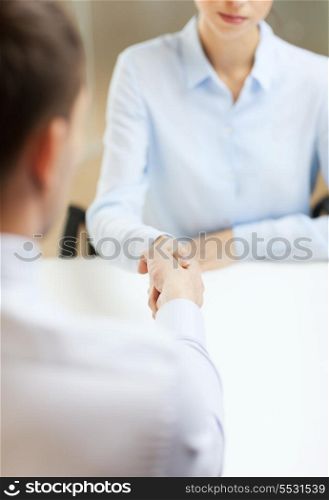 business and office concept - businesswoman and businessman shaking hands in office
