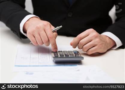 business and office concept - close up of businessman with papers and calculator