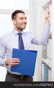 business and office concept - handsome businessman holding folder and picking another one at office