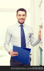 business and office concept - handsome businessman holding folder and picking another one at office