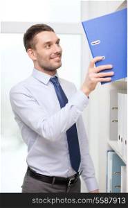 business and office concept - handsome businessman picking folder at office