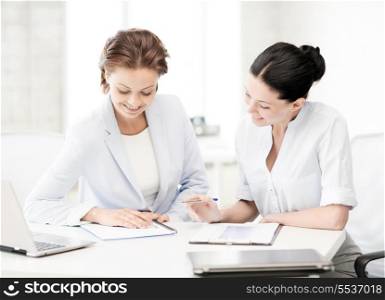 business and office concept - picture of two smiling businesswomen working in office
