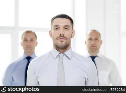 business and office concept - serious businessman in office with team on the back