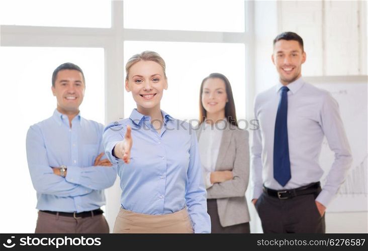 business and office concept - smiling beautiful businesswoman ready for handshake with team in office