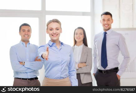 business and office concept - smiling beautiful businesswoman ready for handshake with team in office