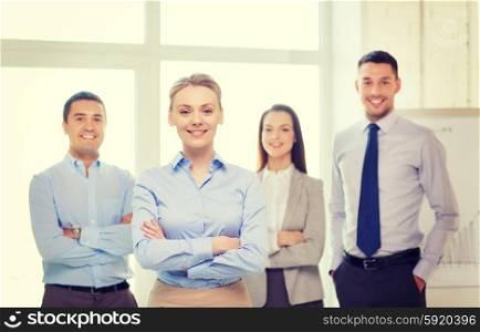 business and office concept - smiling beautiful businesswoman with crossed hands and team in office. smiling businesswoman in office with team on back
