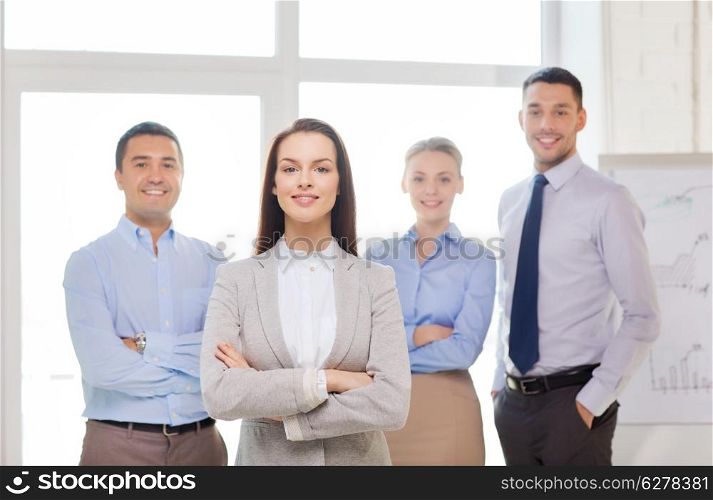 business and office concept - smiling beautiful businesswoman with crossed hands and team in office