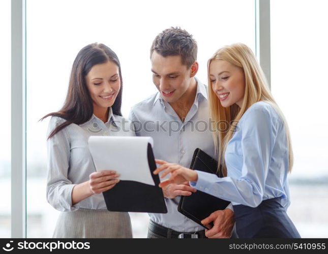 business and office concept - smiling business team looking at clipboard