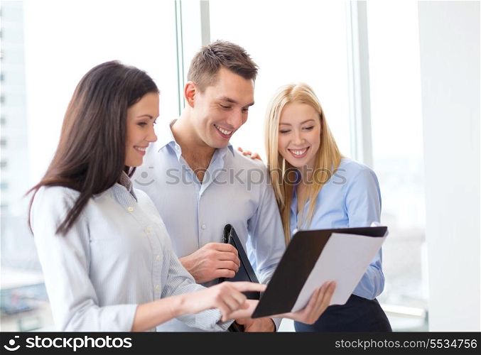 business and office concept - smiling business team looking at clipboard
