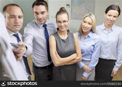 business and office concept - smiling business team with charts on flip board having discussion