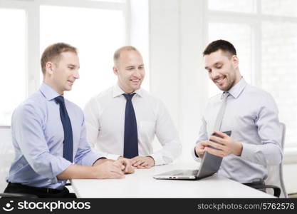 business and office concept - smiling business team working with laptop computer in office