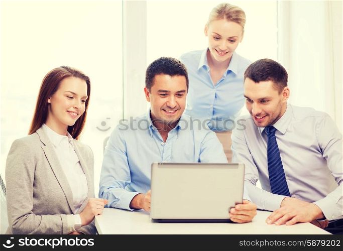 business and office concept - smiling business team working with laptop computer in office. business team working with laptop in office