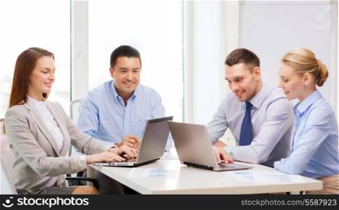 business and office concept - smiling business team working with laptop computers in office