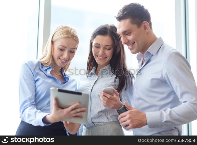 business and office concept - smiling business team working with tablet pcs and smartphones in office