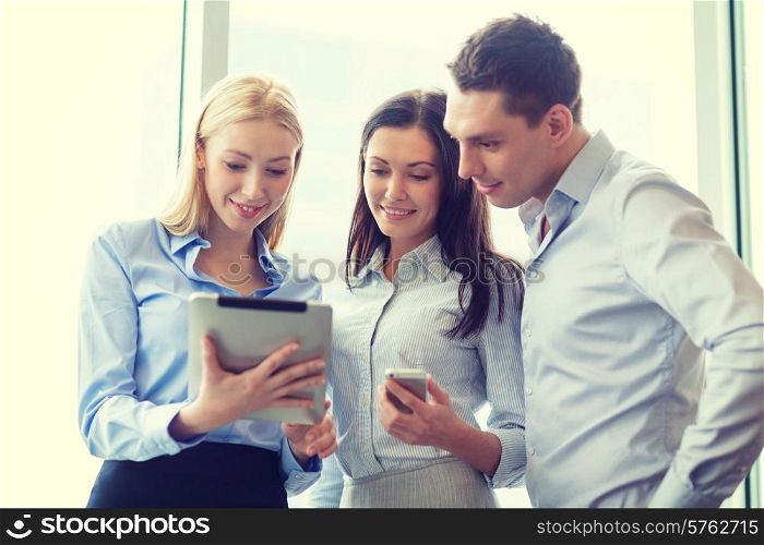 business and office concept - smiling business team working with tablet pcs and smartphones in office