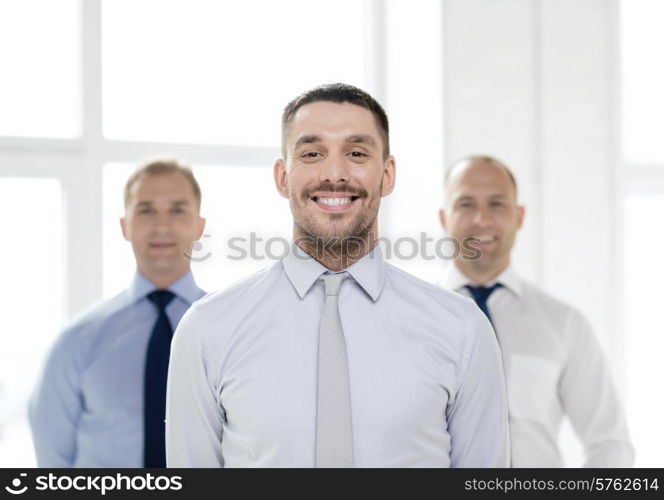 business and office concept - smiling businessman in office with team on the back