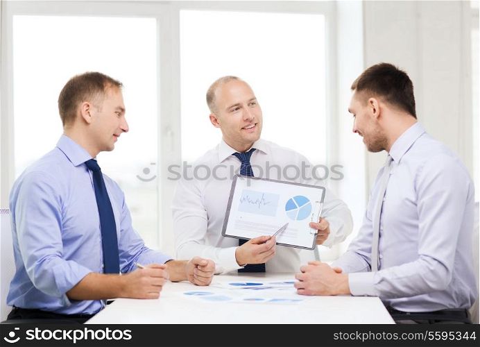 business and office concept - smiling businessman showing others charts in office
