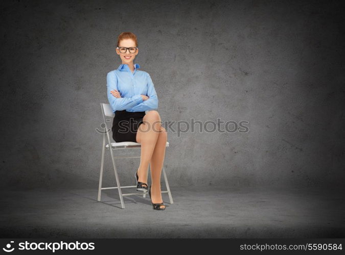 business and office concept - smiling businesswoman in eyeglasses sitting on a chair