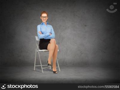business and office concept - smiling businesswoman in eyeglasses sitting on a chair