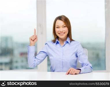 business and office concept - smiling businesswoman pointing finger up in office