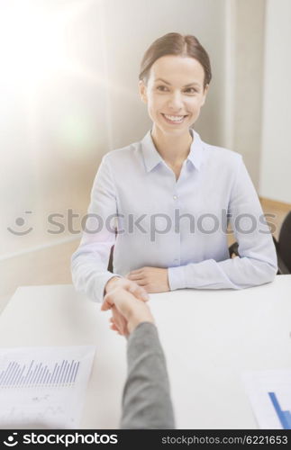 business and office concept - smiling businesswoman shaking hand in office. smiling businesswoman shaking hand in office