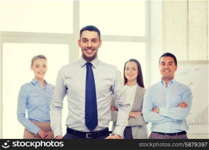 business and office concept - smiling handsome businessman with team in office. smiling businessman in office with team on back