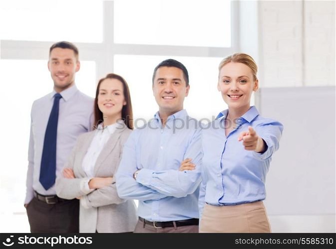 business and office concept - smiling handsome businesswoman with team in office pointing finger at you
