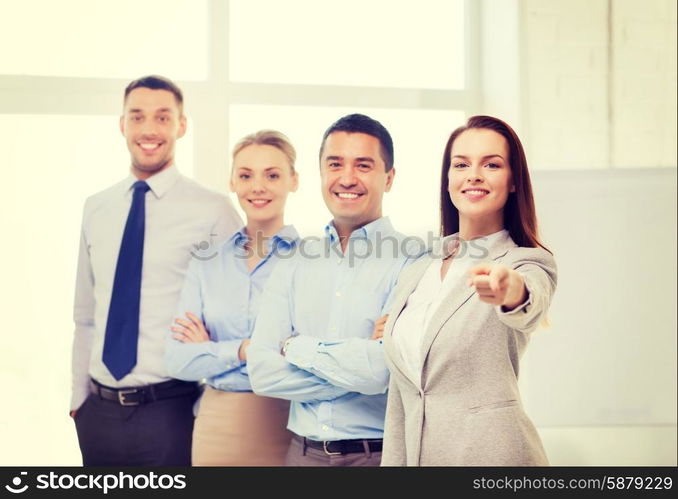 business and office concept - smiling handsome businesswoman with team in office pointing finger at you. businesswoman in office pointing finger at you