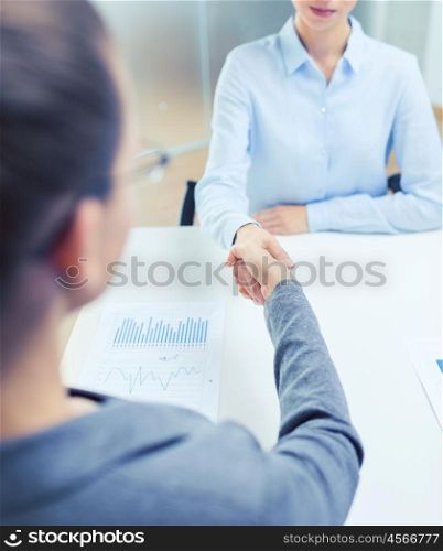 business and office concept - two calm businesswoman shaking hands in office. two calm businesswoman shaking hands in office