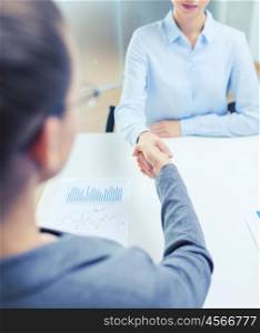 business and office concept - two calm businesswoman shaking hands in office. two calm businesswoman shaking hands in office