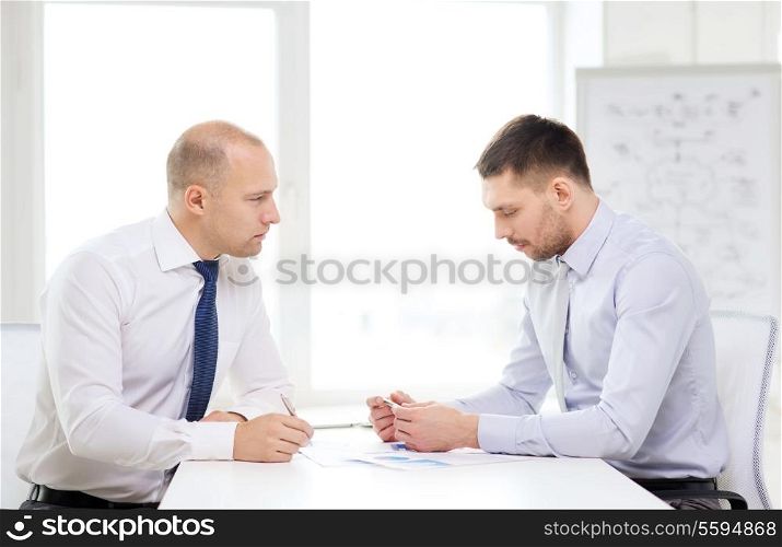 business and office concept - two serious businessman with papers in office