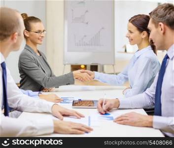 business and office concept - two smiling businesswoman shaking hands in office